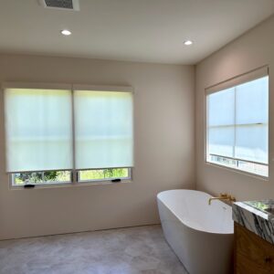 Sleek, modern bathroom with white roller shades on the windows.