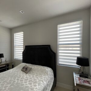 Bedroom with zebra shades, or banded shades, on two windows.