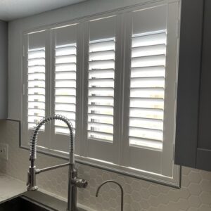 Sleek, modern kitchen interior with plantation shutters or indoor shutters on the window above the kitchen sink.