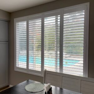 Large dining room windows with white plantation shutters or indoor shutters.