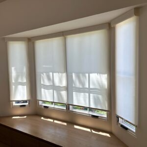 White roller shades on large living room windows.